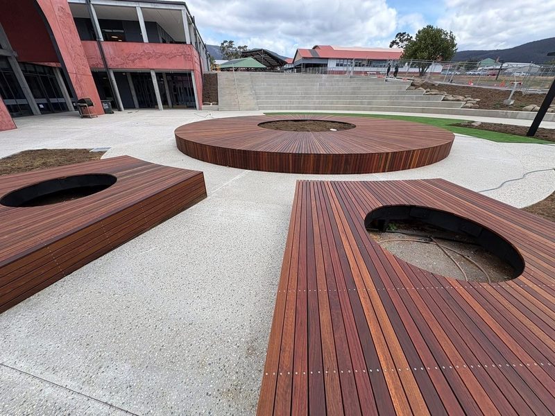 Circular hardwood seating decks with tree cutouts, formed and built in place at a commercial school project.