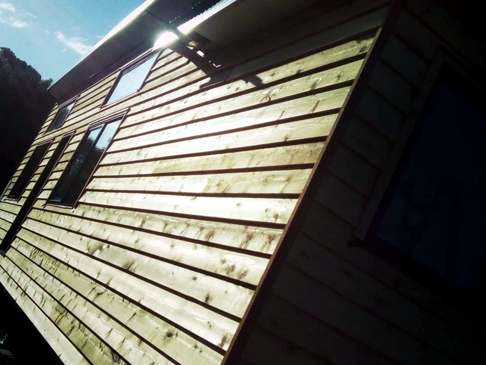 Horizontal timber weatherboard cladding on a home, photographed in low sun from an upward angle.
